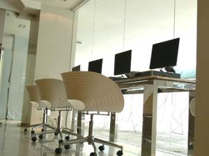 曼谷Tango Vibrant Living Hotel - SHA Extra Plus的办公室,配有桌子、几把椅子和一台电脑