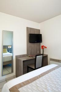 克莱蒙费朗塞祖尔阿菲尔克雷蒙费兰德共和公园酒店的一间卧室配有一张床和一张书桌及电视