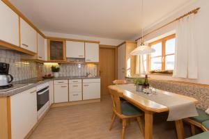 菲伯布伦Bio-Bauernhof Niederlehen的厨房配有白色橱柜和木桌