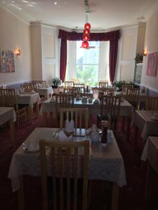 道格拉斯Adelphi Guest House的餐厅设有桌椅和大窗户。