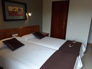 圣马尔廷德尔卡斯塔尼亚尔Hostal Rural El Campito的配有衬衫的酒店客房内的两张床