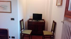 雷诺河畔卡萨莱基奥Casina Belvedere的一间配有电视的房间,配有一个柜子和两把椅子