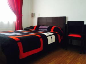 伊皮亚莱斯Hotel San José Ipiales的一张带黑色和红色毯子的床和一把椅子