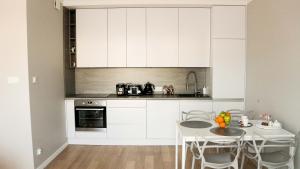 乔左维尔考普尔斯基Apartament Olimp的厨房配有白色橱柜和桌椅