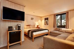 GsteigHotel Sanetsch的配有一张床和一台平面电视的酒店客房