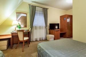 塔尔努夫Hotel Krzyski的酒店客房配有一张床、一张书桌和一台电视。