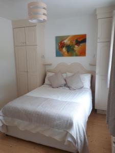 基拉尼Inisfail的卧室配有一张白色床,墙上挂有绘画作品