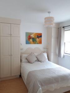 基拉尼Inisfail的白色卧室配有一张床,墙上挂着一幅画