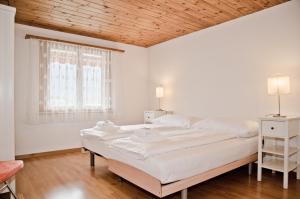 格尔兹维尔Apartment Aare 3.5 by GriwaRent AG的白色卧室设有两张床和木制天花板
