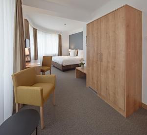 卢森堡城市酒店的酒店客房配有一张床、椅子和橱柜。