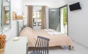 加利萨斯Syros INN的一间卧室配有一张带粉红色床单和椅子的床