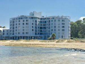 斯特兰德False Bay Inn的靠近水面的海滩上一座白色的大建筑