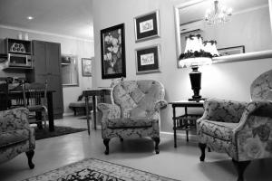 惠灵顿Versailles Self-Catering的客厅配有椅子、桌子和台灯