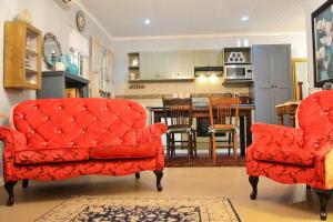 惠灵顿Versailles Self-Catering的一间带两张红色椅子的客厅和一间厨房