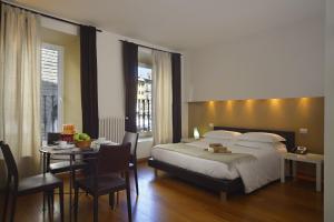 佛罗伦萨瑞雷斯广场酒店的一间卧室配有一张床铺和一张桌子,还有一间用餐室