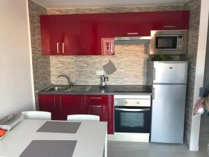 阿德耶Bonito apartamento Complejo Orlando的厨房配有红色橱柜和白色冰箱