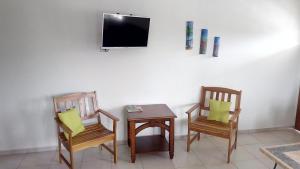 斯卡伯勒Michael's Tropical Suites的两把椅子和一张桌子,墙上配有电视