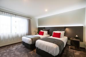 罗托鲁瓦金斯和平汽车旅馆的两张位于酒店客房的床铺,配有红色枕头