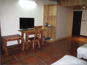 龙胜龙脊平安假日酒店的客房设有一张桌子、一台电视和一张床