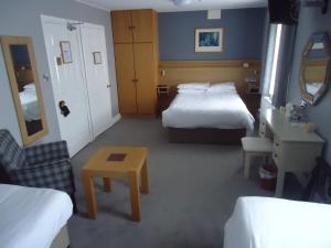 坦普尔莫尔Templemore Arms Hotel的酒店客房设有两张床、一张桌子和一张桌子。