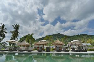 瑟克通龙目岛套房度假村的一个带椅子和遮阳伞的度假游泳池
