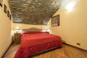 普雷圣迪迪埃Apartment in Pre Saint Didier的一间卧室配有一张红色的床和石墙