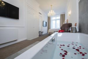 布尔诺Apartmány Arte的客厅设有大型白色浴缸,地板上摆放着红色玫瑰