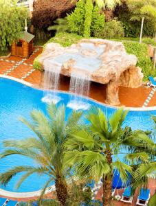 萨洛H10萨拉乌里斯皇宫酒店的一个带瀑布和棕榈树的游泳池