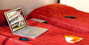 布雷达布雷达普瑞米尔经典酒店的床上的笔记本电脑