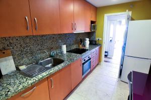 EsteponaBenatalaya Estepona的厨房配有木制橱柜、水槽和冰箱。