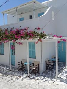 安迪帕罗斯岛Galanis Place的白色的建筑,配有桌椅和粉红色的鲜花