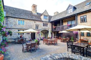 彼得伯勒The Bell Inn, Stilton, Cambridgeshire的一个带桌椅和遮阳伞的户外庭院。