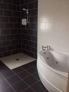 多尼戈尔Leghowney House的浴室设有白色浴缸和黑色瓷砖。