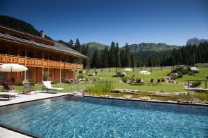 阿尔卑斯休斯山Dolomites Living Hotel Tirler的大楼前的大型游泳池