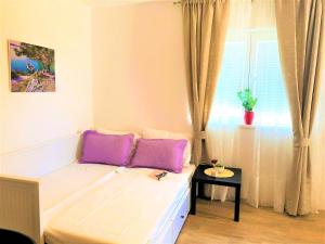 罗佐瓦克Apartments Village的客房配有一张带紫色枕头的床和窗户。