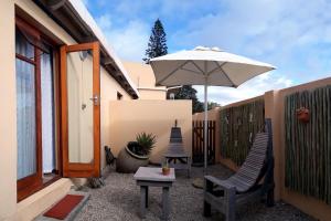 莫塞尔湾Avenues Guesthouse的庭院配有两把椅子和一把遮阳伞