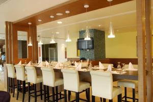 海得拉巴海得拉巴达斯帕拉酒店的餐厅设有长长的酒吧,配有白色椅子