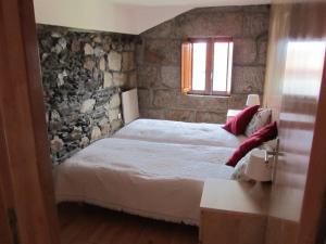 塔布阿苏Casa Da Tia Em Tabuaço的一间卧室设有一张床和石墙