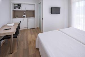 萨洛玛琳娜达公寓式酒店的一间带一张床和一张书桌的卧室和一间厨房