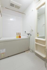 泉佐野ABC民宿的一间白色浴室,在架子上装有瓶子