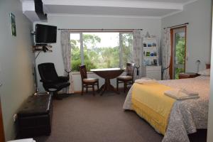 Portobello树顶膳宿旅馆的一间卧室配有一张床、一张桌子和一个窗户。