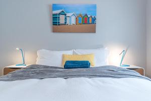 悉尼海滩度假公寓的一张带两盏灯的床和一幅海滩房屋画