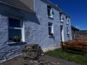 丁格尔Old Irish farmhouse的蓝色的建筑,前面设有木凳