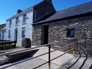 丁格尔Old Irish farmhouse的旁边一座石头建筑,旁边设有长凳