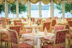 施坦贝尔格湖畔贝格莱尼赛酒店的一间带桌椅和水的餐厅