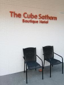 曼谷The Cube Sathorn Boutique Hotel เดอะ คิวบ์ สาทร บูติค โฮเทล Near BTS Surasak的两把椅子坐在酒店标志前