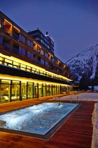 大格洛克纳山麓卡尔斯格拉多纳山木屋度假酒店的一座在夜间设有游泳池的建筑,有积雪覆盖的山脉