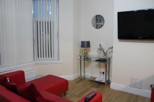 卡菲利Van Apartments的客厅配有红色沙发和平面电视