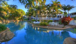 库克敦索维度假酒店的度假村内一座带棕榈树和椅子的游泳池