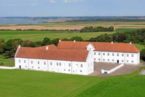RanumDanhostel Vitskøl Kloster的一座白色的大建筑,在田野上设有红色屋顶